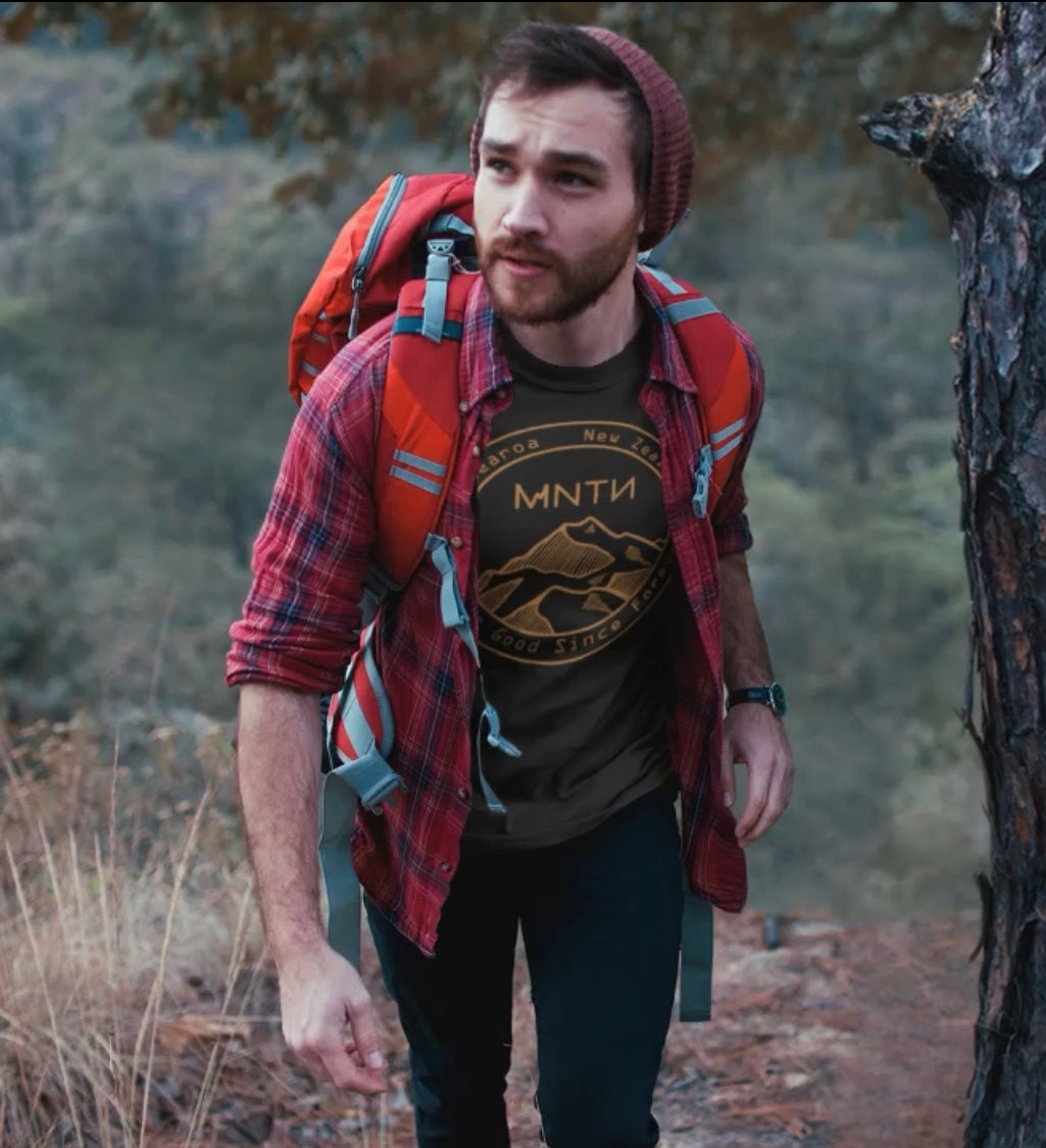 Man walking through the mountains with a mntn tee shirt on